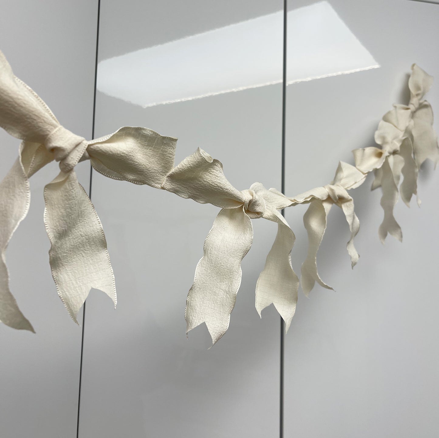 Ribbon Bow Garland Hanging against white background. 10 Bows per garland.