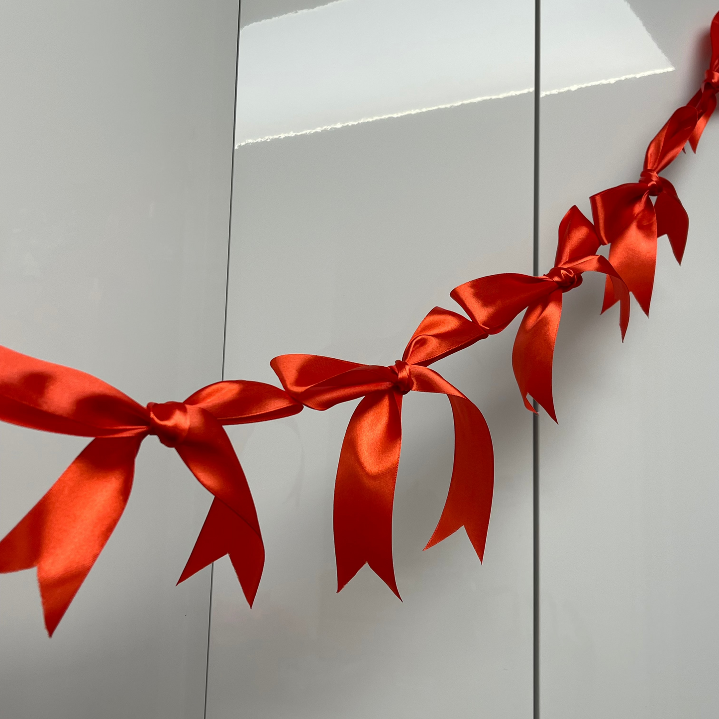 Orange Pink Satin Bow Garland hanging against a white background. 10 Bows per garland.