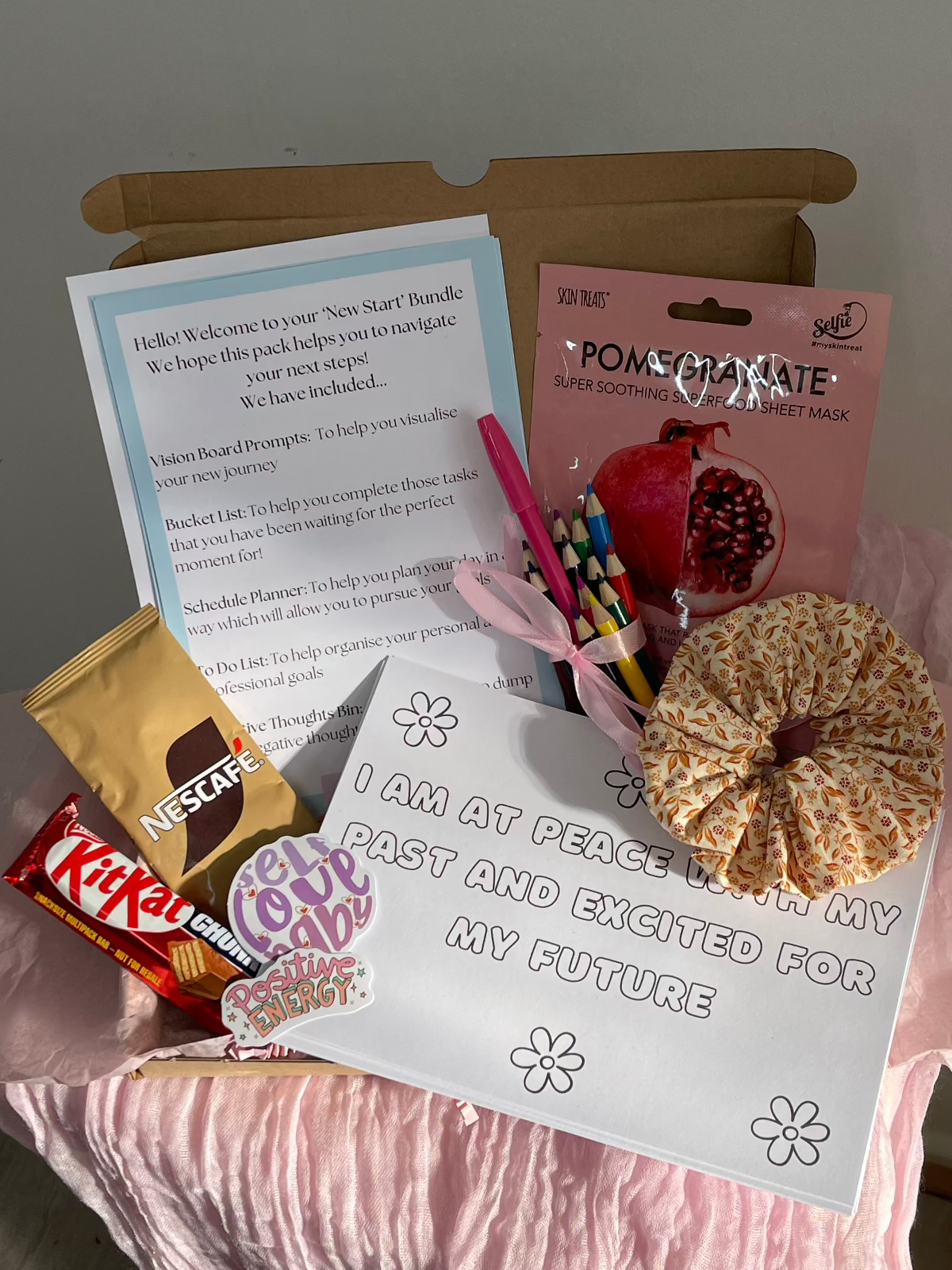 Image of 'New Start Bundle Self-Care Gift Box' which contains: 
New Start Bundle Motivation Kit
x10 Positive Affirmation Colouring Sheets
Motivational Stickers
Facemask
Handmade Scrunchie 
Coffee Satchet
Kit Kat 
Colouring Pencils 
Pink Pen 